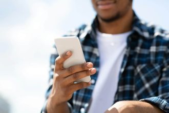 Homme afro-américain envoyant un SMS avec son smartphone